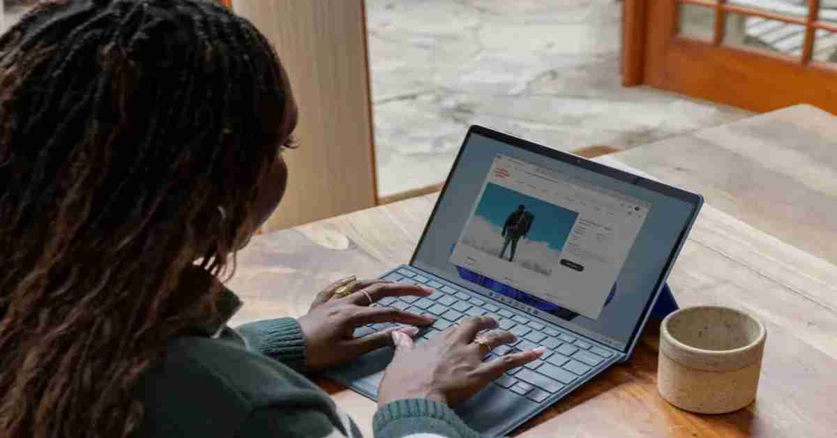 a woman sitting at a table using a laptop computer scaled copy 1200x628 ezgif.com webp to jpg converter 2